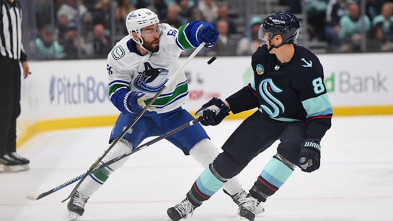 Nov 24, 2023; Seattle, Washington, USA; Vancouver Canucks defenseman Mark Friedman (51) and Seattle Kraken defenseman Brian Dumoulin (8) play the puck during the first period at Climate Pledge Arena. Mandatory Credit: Steven Bisig-USA TODAY Sports