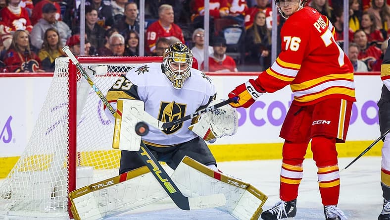 Nov 27, 2023; Calgary, Alberta, CAN; Vegas Golden Knights goaltender Adin Hill (33) guards his net as Calgary Flames center Martin Pospisil (76) tries to redirect the puck during the second period at Scotiabank Saddledome. Mandatory Credit: Sergei Belski-USA TODAY Sports