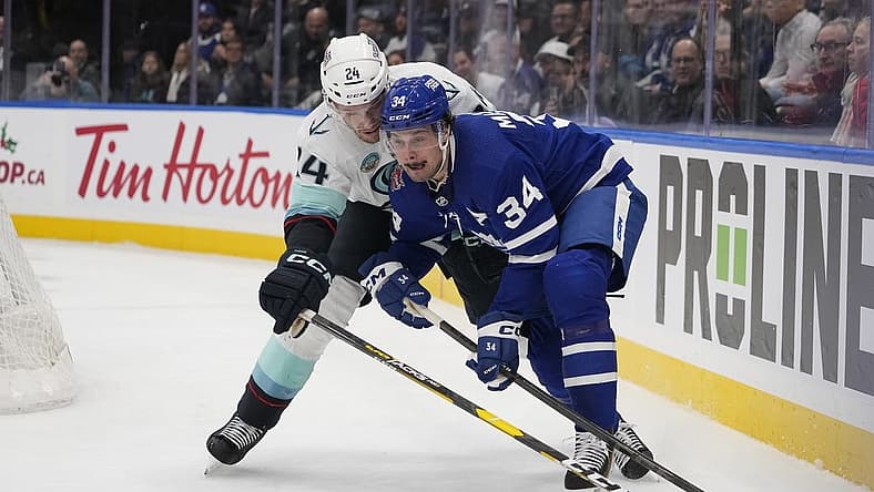 Nov 30, 2023; Toronto, Ontario, CAN; Toronto Maple Leafs forward Auston Matthews (34) battles with Seattle Kracken defenseman Jamie Oleksiak (24) for the puck during the first period at Scotiabank Arena. Mandatory Credit: John E. Sokolowski-USA TODAY Sports