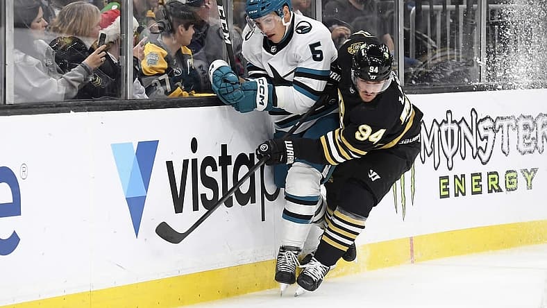 Nov 30, 2023; Boston, Massachusetts, USA; Boston Bruins center Jakub Lauko (94) checks San Jose Sharks defenseman Matt Benning (5) along the boards during the first period at TD Garden. Mandatory Credit: Bob DeChiara-USA TODAY Sports