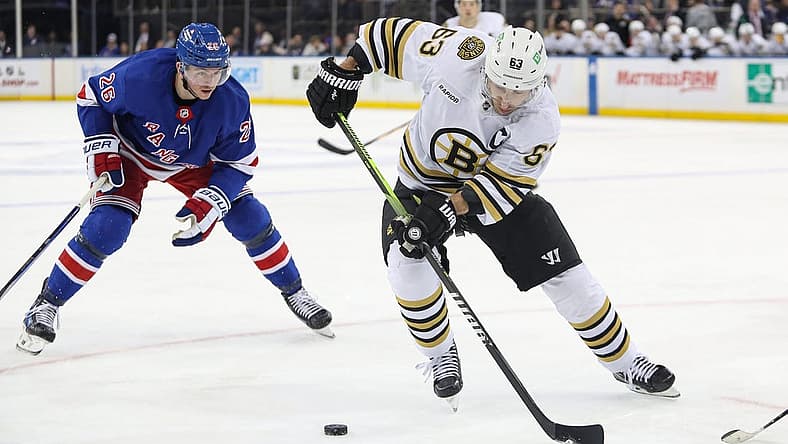 Nov 25, 2023; New York, New York, USA; Boston Bruins left wing Brad Marchand (63) plays the puck in front of New York Rangers left wing Jimmy Vesey (26) during the third period at Madison Square Garden. Mandatory Credit: Danny Wild-USA TODAY Sports