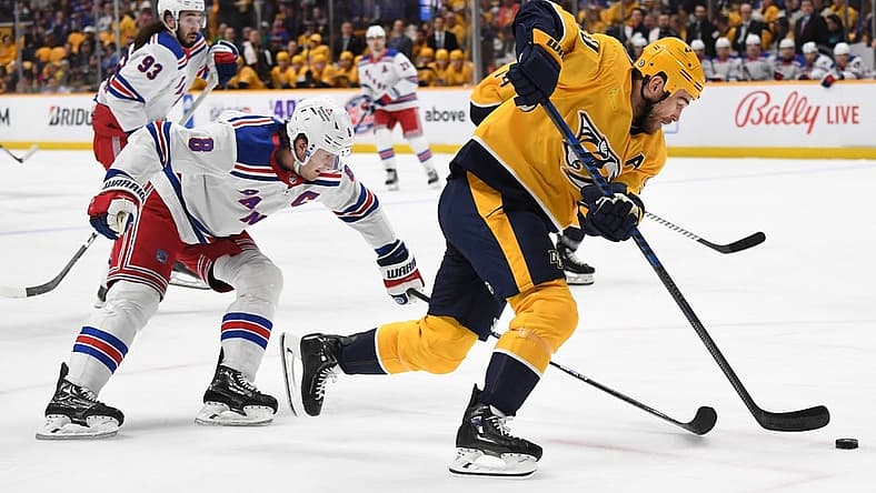 Dec 2, 2023; Nashville, Tennessee, USA; Nashville Predators center Ryan O'Reilly (90) handles the puck against New York Rangers defenseman Jacob Trouba (8) during the first period at Bridgestone Arena. Mandatory Credit: Christopher Hanewinckel-USA TODAY Sports