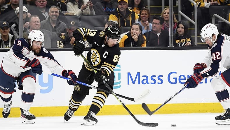 Dec 3, 2023; Boston, Massachusetts, USA; Boston Bruins left wing Brad Marchand (63) tries to control the puck between Columbus Blue Jackets defenseman Ivan Provorov (9) and center Alexandre Texier (42) during the first period at TD Garden. Mandatory Credit: Bob DeChiara-USA TODAY Sports