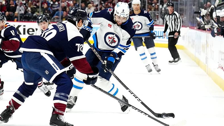 Dec 7, 2023; Denver, Colorado, USA; Winnipeg Jets left wing Alex Iafallo (9) shoots the puck towards Colorado Avalanche defenseman Sam Malinski (70) in the first period at Ball Arena. Mandatory Credit: Ron Chenoy-USA TODAY Sports