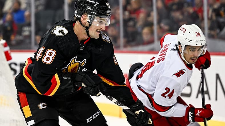 Dec 7, 2023; Calgary, Alberta, CAN; Calgary Flames defenseman Dennis Gilbert (48) competes for the puck against Carolina Hurricanes center Seth Jarvis (24) during the second period of a game at Scotiabank Saddledome. Mandatory Credit: Brett Holmes-USA TODAY Sports