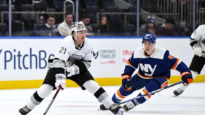 Dec 9, 2023; Elmont, New York, USA; Los Angeles Kings defenseman Jordan Spence (21) skates with the puck while being defended by New York Islanders center Jean-Gabriel Pageau (44) during the first period at UBS Arena. Mandatory Credit: John Jones-USA TODAY Sports