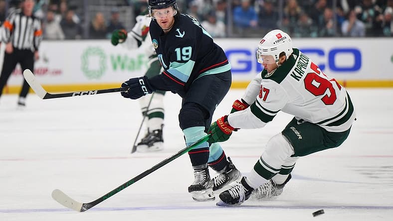 Dec 10, 2023; Seattle, Washington, USA; Seattle Kraken left wing Jared McCann (19) passes the puck past Minnesota Wild left wing Kirill Kaprizov (97) during the first period at Climate Pledge Arena. Mandatory Credit: Steven Bisig-USA TODAY Sports