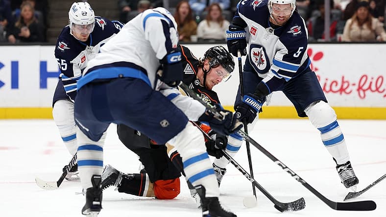 Dec 10, 2023; Anaheim, California, USA; Anaheim Ducks left wing Brock McGinn (26) fights for the puck against Winnipeg Jets defenseman Brenden Dillon (5) during the second period at Honda Center. Mandatory Credit: Kiyoshi Mio-USA TODAY Sports