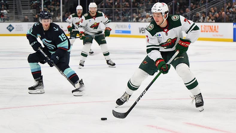 Dec 10, 2023; Seattle, Washington, USA; Minnesota Wild defenseman Brock Faber (7) plays the puck while defended by Seattle Kraken left wing Jared McCann (19) during the third period at Climate Pledge Arena. Mandatory Credit: Steven Bisig-USA TODAY Sports