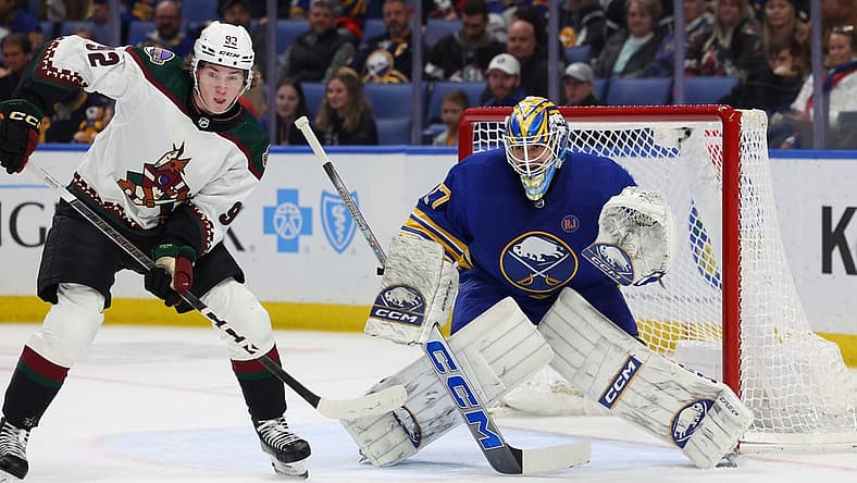 Dec 11, 2023; Buffalo, New York, USA; Arizona Coyotes center Logan Cooley (92) and Buffalo Sabres goaltender Devon Levi (27) look for the puck during the first period at KeyBank Center. Mandatory Credit: Timothy T. Ludwig-USA TODAY Sports
