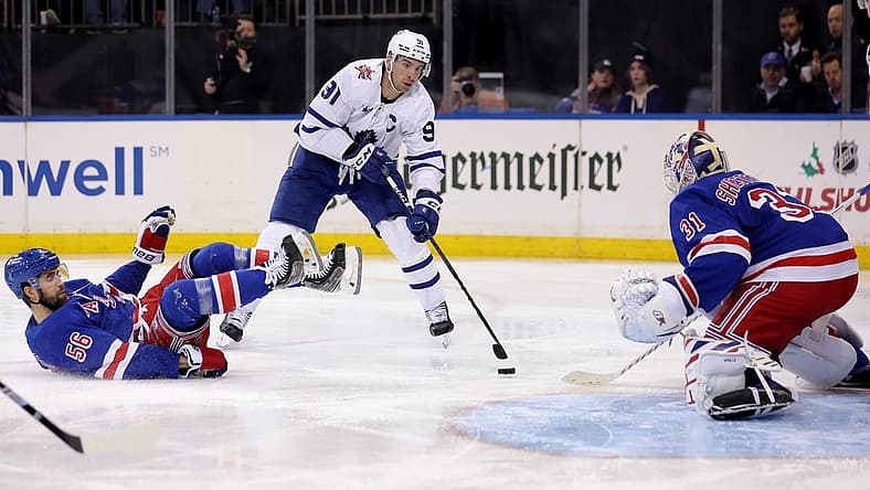 Dec 12, 2023; New York, New York, USA; Toronto Maple Leafs center John Tavares (91) skates with the puck against New York Rangers defenseman Erik Gustafsson (56) and goaltender Igor Shesterkin (31) during the third period at Madison Square Garden. Mandatory Credit: Brad Penner-USA TODAY Sports