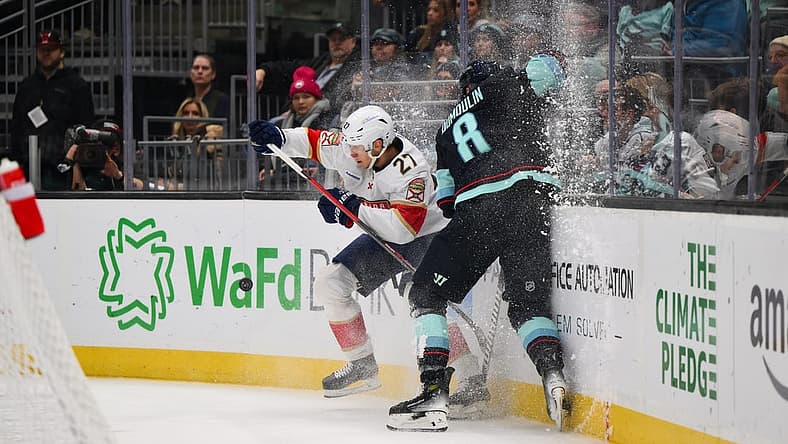 Dec 12, 2023; Seattle, Washington, USA; Florida Panthers center Eetu Luostarinen (27) checks Seattle Kraken defenseman Brian Dumoulin (8) into the wall during the first period at Climate Pledge Arena. Mandatory Credit: Steven Bisig-USA TODAY Sports.