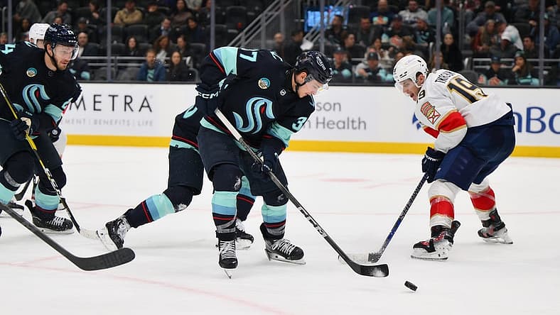 Dec 12, 2023; Seattle, Washington, USA; Seattle Kraken center Yanni Gourde (37) clears the puck away from Florida Panthers left wing Matthew Tkachuk (19) during the third period at Climate Pledge Arena. Mandatory Credit: Steven Bisig-USA TODAY Sports