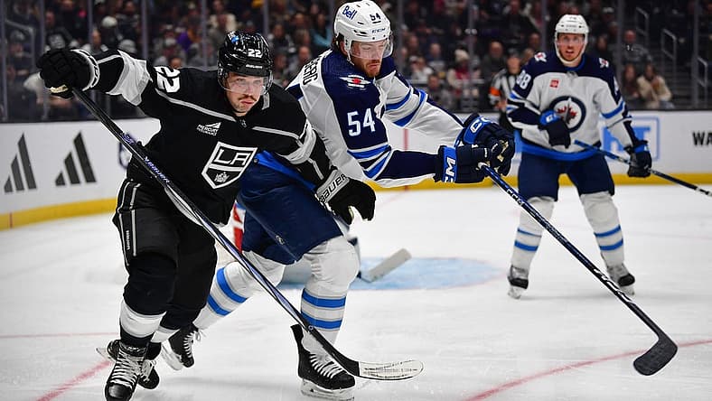 Dec 13, 2023; Los Angeles, California, USA; Los Angeles Kings left wing Kevin Fiala (22) plays for the puck against Winnipeg Jets defenseman Dylan Samberg (54) during the second period at Crypto.com Arena. Mandatory Credit: Gary A. Vasquez-USA TODAY Sports