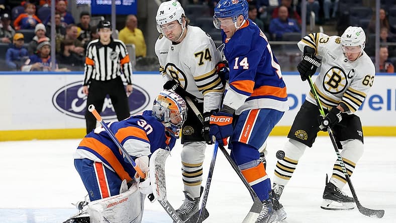 Dec 15, 2023; Elmont, New York, USA; Boston Bruins left wing Jake DeBrusk (74) and left wing Brad Marchand (63) fight for the puck against New York Islanders goaltender Ilya Sorokin (30) and center Bo Horvat (14) during the first period at UBS Arena. Mandatory Credit: Brad Penner-USA TODAY Sports