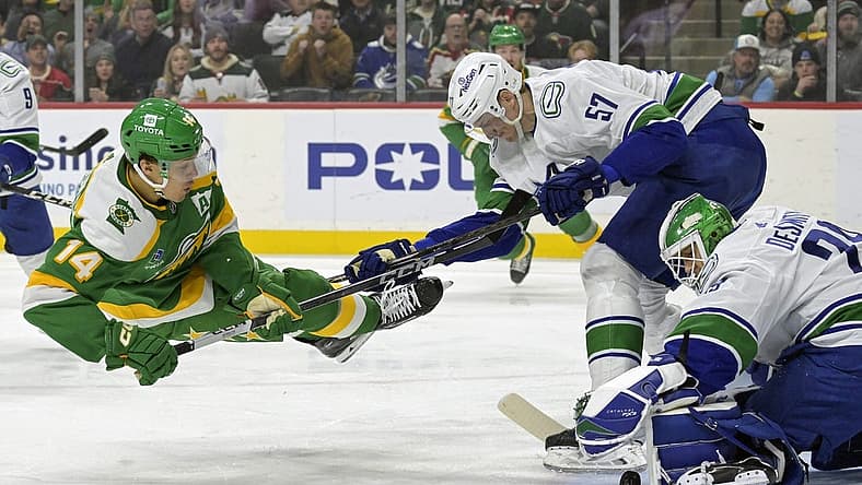 Dec 16, 2023; Saint Paul, Minnesota, USA;  Vancouver Canucks defenseman Tyler Myers (57) sends Minnesota Wild forward Joel Eriksson Ek (14) flying as goalie Casey DeSmith (29) covers the puck during the first period at Xcel Energy Center. Mandatory Credit: Nick Wosika-USA TODAY Sports