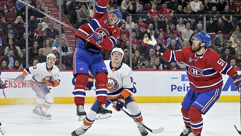 Dec 16, 2023; Montreal, Quebec, CAN; Montreal Canadiens forward Nick Suzuki (14) jumps to reach the puck during the first period of the game against the New York Islanders at the Bell Centre. Mandatory Credit: Eric Bolte-USA TODAY Sports
