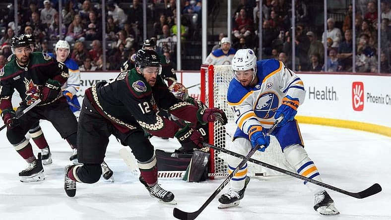 Dec 16, 2023; Tempe, Arizona, USA; Arizona Coyotes left wing Zach Sanford (12) checks Buffalo Sabres defenseman Connor Clifton (75) during the first period at Mullett Arena. Mandatory Credit: Joe Camporeale-USA TODAY Sports