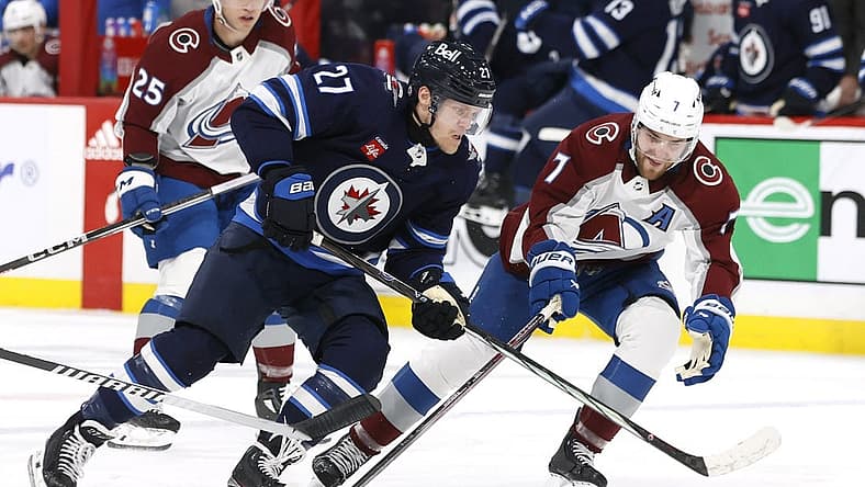 Dec 16, 2023; Winnipeg, Manitoba, CAN; Winnipeg Jets left wing Nikolaj Ehlers (27) is checked by Colorado Avalanche defenseman Devon Toews (7) in the second period at Canada Life Centre. Mandatory Credit: James Carey Lauder-USA TODAY Sports