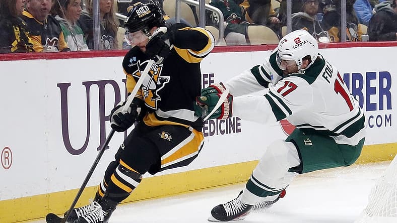 Dec 18, 2023; Pittsburgh, Pennsylvania, USA;  Pittsburgh Penguins defenseman Kris Letang (58) handles the puck against pressure from Minnesota Wild left wing Marcus Foligno (17) during the first period at PPG Paints Arena. Mandatory Credit: Charles LeClaire-USA TODAY Sports