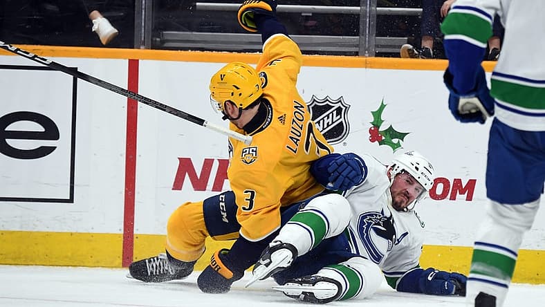 Dec 19, 2023; Nashville, Tennessee, USA; Nashville Predators defenseman Jeremy Lauzon (3) and Vancouver Canucks center J.T. Miller (9) fall to the ice going for a puck in the corner during the second period at Bridgestone Arena. Mandatory Credit: Christopher Hanewinckel-USA TODAY Sports