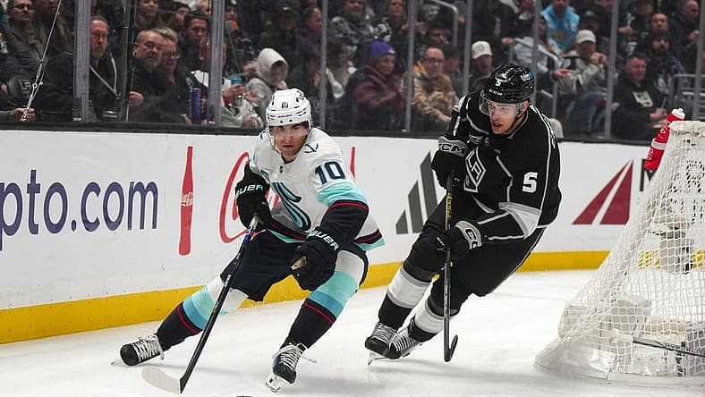 Dec 20, 2023; Los Angeles, California, USA; Seattle Kraken center Matty Beniers (10) and LA Kings defenseman Andreas Englund (5) battle for the puck in the first period at Crypto.com Arena. Mandatory Credit: Kirby Lee-USA TODAY Sports