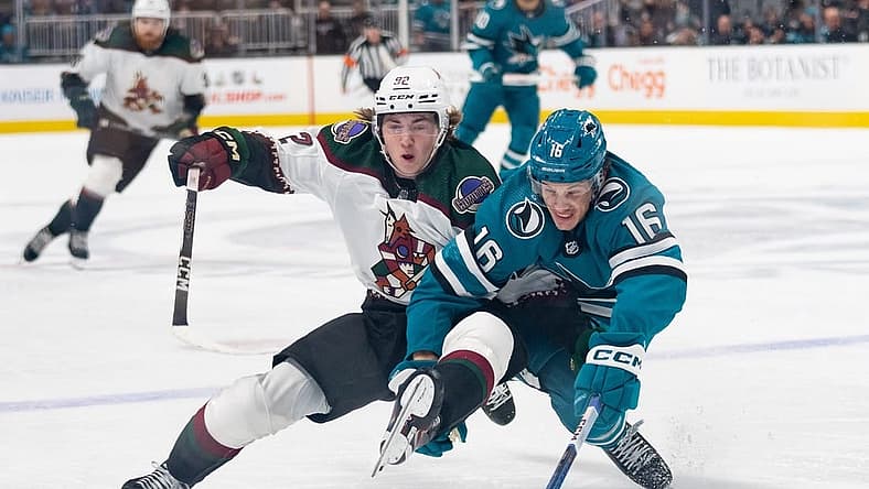 Dec 21, 2023; San Jose, California, USA; Arizona Coyotes center Logan Cooley (92) and San Jose Sharks center Jack Studnicka (16) collides during the first period at SAP Center at San Jose. Mandatory Credit: Stan Szeto-USA TODAY Sports