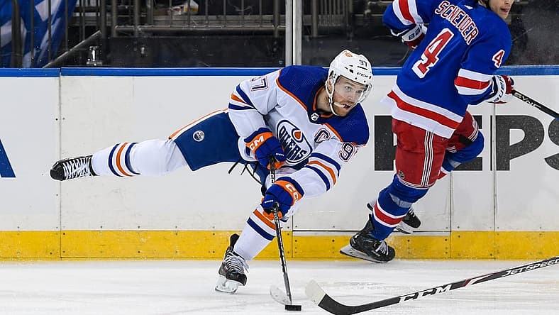 Dec 22, 2023; New York, New York, USA;  Edmonton Oilers center Connor McDavid (97) passes the puck against the New York Rangers during the third period at Madison Square Garden. Mandatory Credit: Dennis Schneidler-USA TODAY Sports