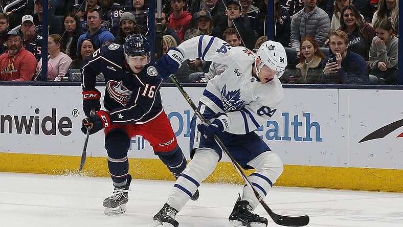 Dec 23, 2023; Columbus, Ohio, USA; Toronto Maple Leafs center David Kampf (64) picks up a loose puck as Columbus Blue Jackets center Brendan Gaunce (16) trails the play during the first period at Nationwide Arena. Mandatory Credit: Russell LaBounty-USA TODAY Sports