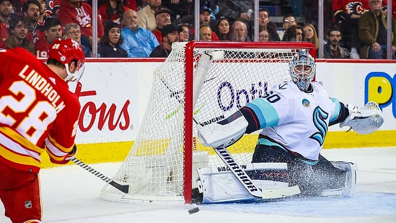 Dec 27, 2023; Calgary, Alberta, CAN; Seattle Kraken goaltender Chris Driedger (60) makes a save against Calgary Flames center Elias Lindholm (28) during the second period at Scotiabank Saddledome. Mandatory Credit: Sergei Belski-USA TODAY Sports