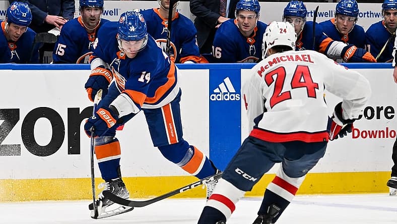 Dec 29, 2023; Elmont, New York, USA; New York Islanders center Bo Horvat (14) keeps the puck in the zone defended by Washington Capitals center Connor McMichael (24) during the second period at UBS Arena. Mandatory Credit: Dennis Schneidler-USA TODAY Sports