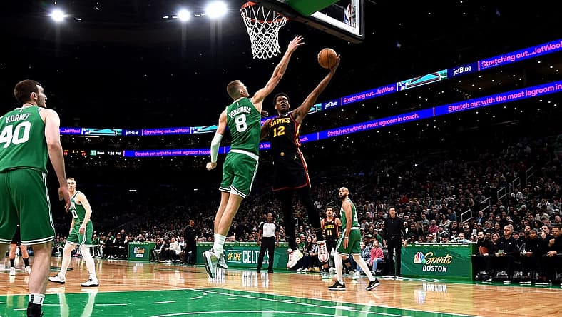 Feb 7, 2024; Boston, Massachusetts, USA; Atlanta Hawks forward De'Andre Hunter (12) drives to the basket and gets fouled by Boston Celtics center Kristaps Porzingis (8) during the first half at TD Garden. Mandatory Credit: Bob DeChiara-USA TODAY Sports