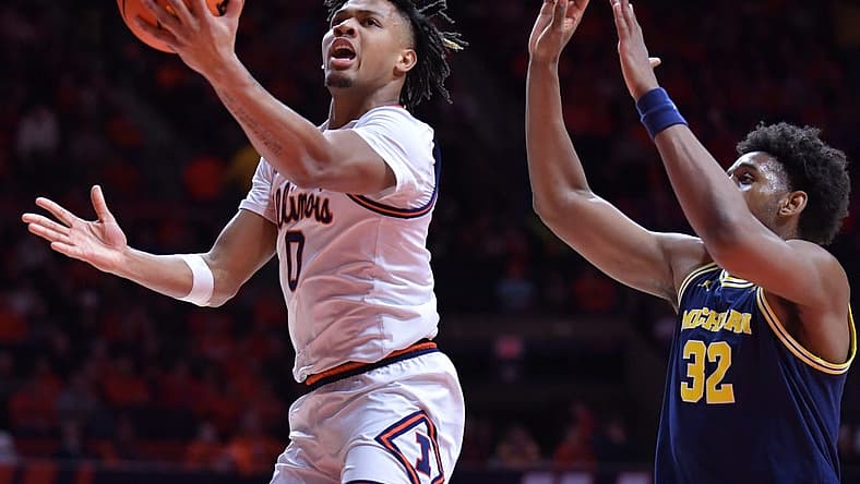 Feb 13, 2024; Champaign, Illinois, USA; Illinois Fighting Illini guard Terrence Shannon Jr. (0) drives past Michigan Wolverines forward Tarris Reed Jr. (32) on his way to the basket during the first half at State Farm Center. Mandatory Credit: Ron Johnson-USA TODAY Sports