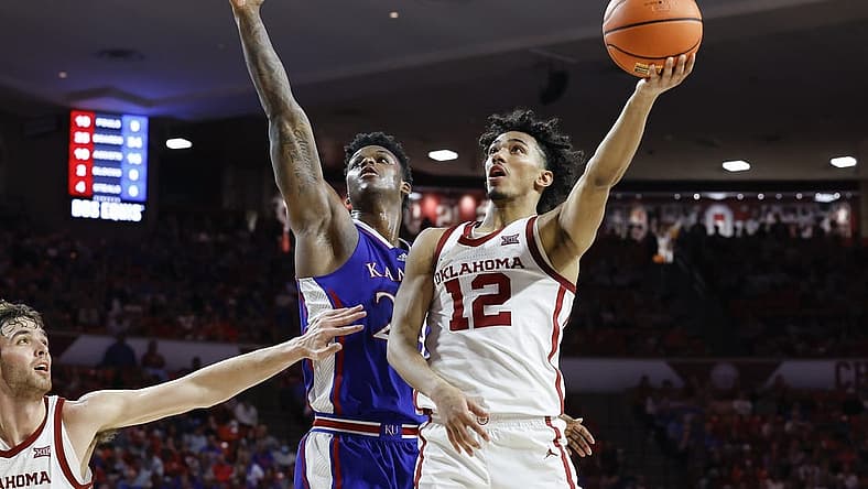 Feb 17, 2024; Norman, Oklahoma, USA; Oklahoma Sooners guard Milos Uzan (12) goes up for a basket beside Kansas Jayhawks forward K.J. Adams Jr. (24) during the second half at Lloyd Noble Center. Mandatory Credit: Alonzo Adams-USA TODAY Sports
