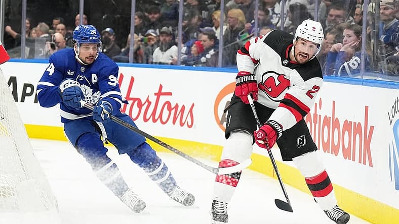 Mar 26, 2024; Toronto, Ontario, CAN; Toronto Maple Leafs center Auston Matthews (34) battles for the puck with New Jersey Devils defenseman Brendan Smith (2) during the first period at Scotiabank Arena. Mandatory Credit: Nick Turchiaro-USA TODAY Sports