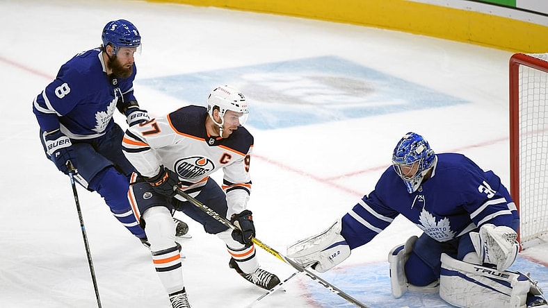 Jan 20, 2021; Toronto, Ontario, CAN; Edmonton Oilers forward Connor McDavid (97) cuts between Toronto Maple Leafs goalie Frederik Andersen (31) and defenseman Jake Muzzin (8) in the first period at Scotiabank Arena. Mandatory Credit: Dan Hamilton-USA TODAY Sports