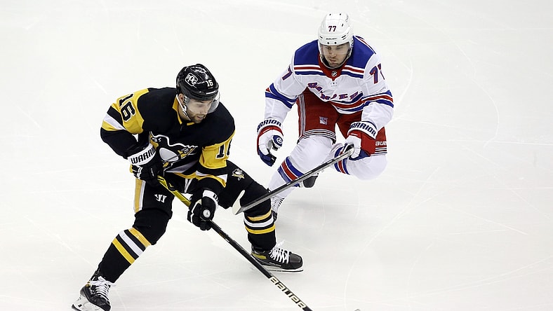 Jan 24, 2021; Pittsburgh, Pennsylvania, USA;  Pittsburgh Penguins left wing Jason Zucker (16) moves the puck against New York Rangers defenseman Tony DeAngelo (77) during the first period at the PPG Paints Arena. Mandatory Credit: Charles LeClaire-USA TODAY Sports