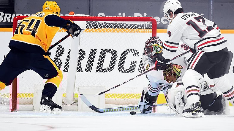 Jan 26, 2021; Nashville, Tennessee, USA; Chicago Blackhawks goaltender Malcolm Subban (30) covers a puck in the crease against  Nashville Predators center Mikael Granlund (64) during the second period at Bridgestone Arena. Mandatory Credit: Christopher Hanewinckel-USA TODAY Sports