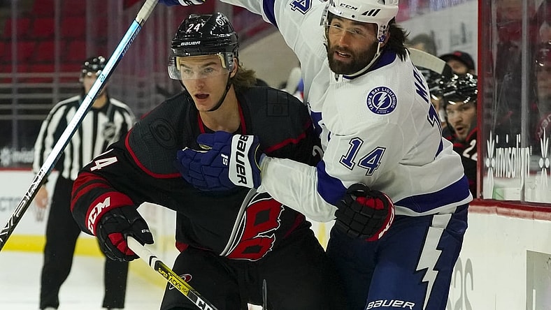 Jan 28, 2021; Raleigh, North Carolina, USA;  Carolina Hurricanes defensemen Jake Bean (24) and Tampa Bay Lightning left wing Pat Maroon (14 watch the play during the first period at PNC Arena. Mandatory Credit: James Guillory-USA TODAY Sports
