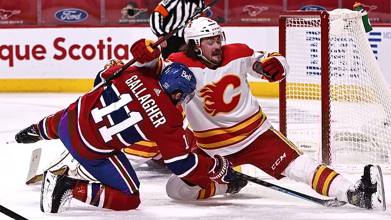 Jan 30, 2021; Montreal, Quebec, CAN; Calgary Flames defenseman Rasmus Andersson (4) and Montreal Canadiens right wing Brendan Gallagher (11) fall in front of goaltender Jacob Markstrom (25) during the second period at Bell Centre. Mandatory Credit: Jean-Yves Ahern-USA TODAY Sports