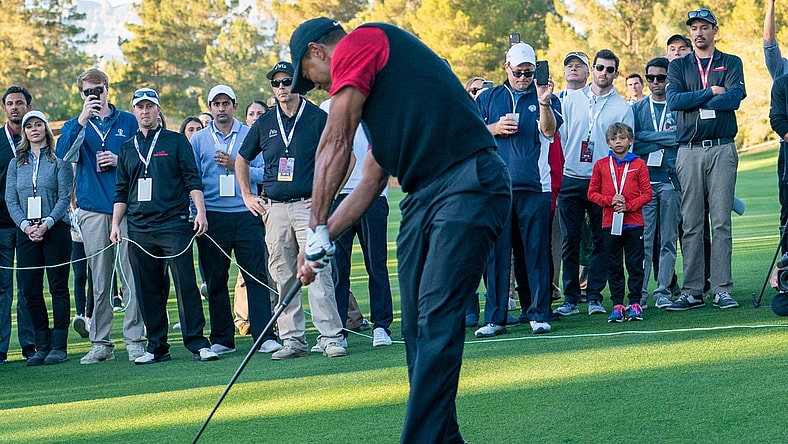 November 23, 2018; Las Vegas, NV, USA; Charlie Woods (red long sleeve) watches father Tiger Woods (left) hit his fairway shot on the 16th hole during The Match: Tiger vs Phil golf match at Shadow Creek Golf Course. Mandatory Credit: Kyle Terada-USA TODAY Sports