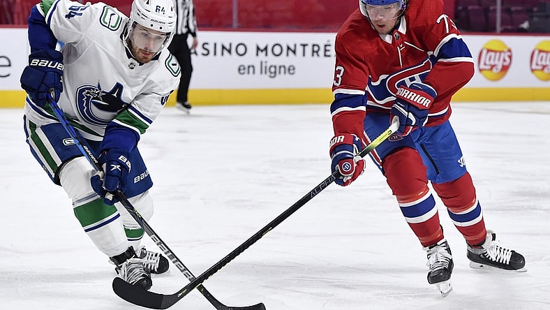 Feb 1, 2021; Montreal, Quebec, CAN; Montreal Canadiens forward Tyler Toffoli (73) plays the puck and Vancouver Canucks forward Tyler Motte (64) defends during the second period at the Bell Centre. Mandatory Credit: Eric Bolte-USA TODAY Sports