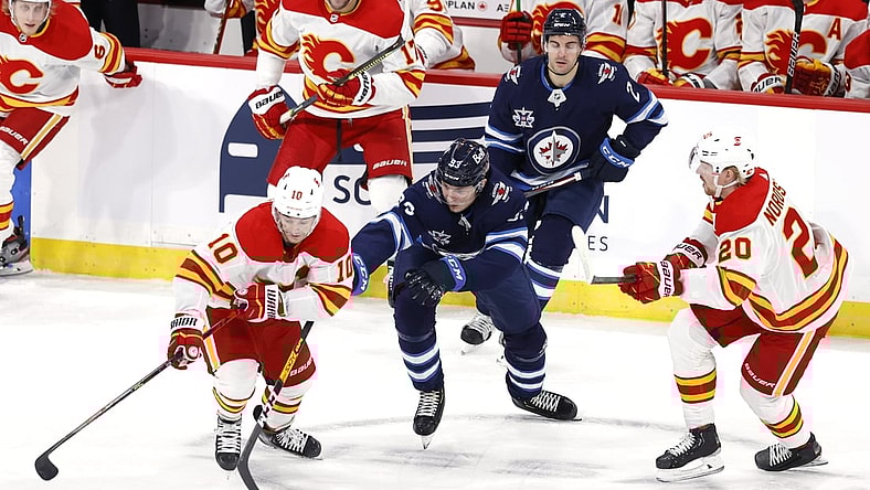 Feb 2, 2021; Winnipeg, Manitoba, CAN.;  Winnipeg Jets Left Wing Kristian Vesalainen (93)  drives for the puck between Calgary Flames center Derek Ryan (10) and Calgary Flames center Joakim Nordstrom (20) in the first period at Bell MTS Place. Mandatory Credit: James Carey Lauder-USA TODAY Sports