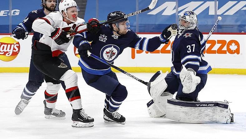 Feb 11, 2021; Winnipeg, Manitoba, CAN; Winnipeg Jets left wing Nikolaj Ehlers (27) gloves down the puck after Ottawa Senators left wing Brady Tkachuk (7) took a shot on goaltender Connor Hellebuyck (37) in the first period at Bell MTS Place. Mandatory Credit: James Carey Lauder-USA TODAY Sports