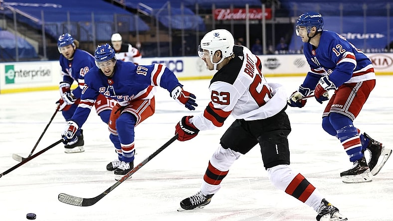 Feb 16, 2021; New York, New York, USA;  Jesper Bratt #63 of the New Jersey Devils takes a shot as Kevin Rooney #17 and Julien Gauthier #12 of the New York Rangers defend during the first period at Madison Square Garden. Mandatory Credit:  Elsa/POOL PHOTOS-USA TODAY Sports