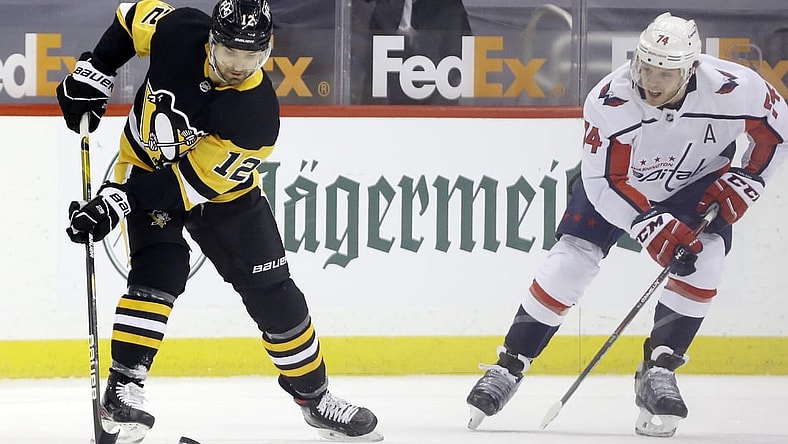 Feb 14, 2021; Pittsburgh, Pennsylvania, USA;  Pittsburgh Penguins center Zach Aston-Reese (12) handles the puck against Washington Capitals defenseman John Carlson (74) during the first period at PPG Paints Arena. Pittsburgh won 6-3. Mandatory Credit: Charles LeClaire-USA TODAY Sports
