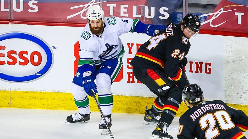 Feb 17, 2021; Calgary, Alberta, CAN; Vancouver Canucks defenseman Jordie Benn (8) and Calgary Flames right wing Brett Ritchie (24) battle for the puck during the first period at Scotiabank Saddledome. Mandatory Credit: Sergei Belski-USA TODAY Sports
