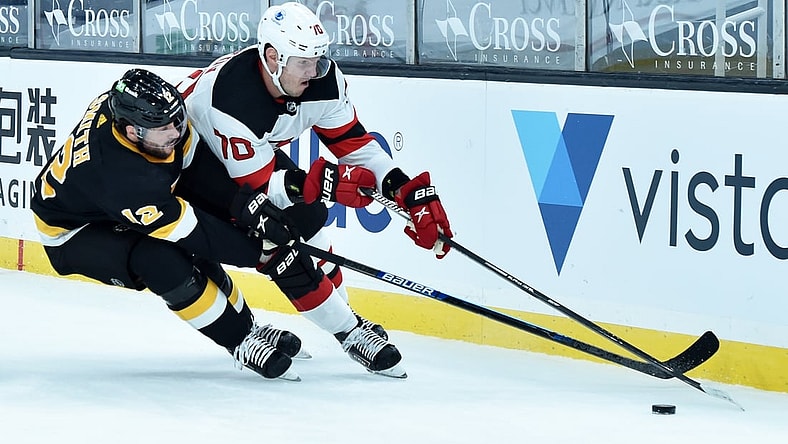Feb 18, 2021; Boston, Massachusetts, USA;  Boston Bruins right wing Craig Smith (12) tries to poke the puck away from New Jersey Devils defenseman Dmitry Kulikov (70) during the first period at TD Garden. Mandatory Credit: Bob DeChiara-USA TODAY Sports