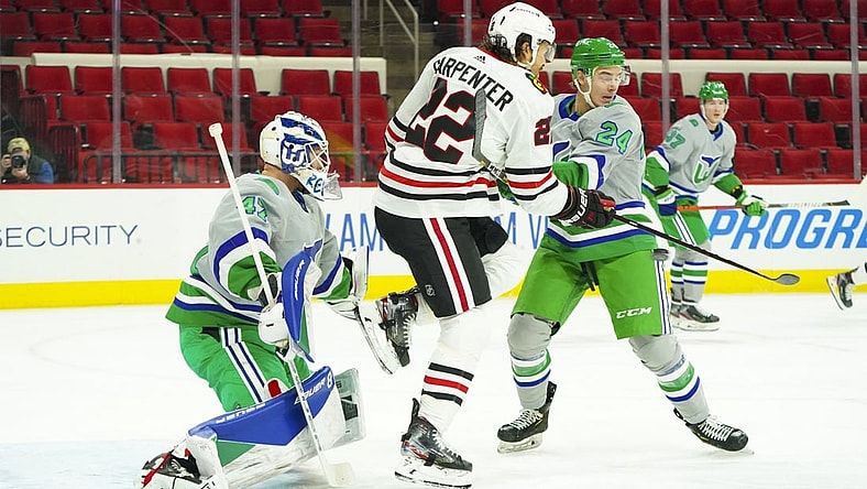Feb 19, 2021; Raleigh, North Carolina, USA;  Carolina Hurricanes goaltender James Reimer (47) defenseman Jake Bean (24) and Chicago Blackhawks center Ryan Carpenter (22) watch the shot in the first period at PNC Arena. Mandatory Credit: James Guillory-USA TODAY Sports