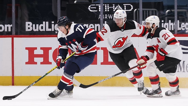 Feb 21, 2021; Washington, District of Columbia, USA; Washington Capitals right wing T.J. Oshie (77) skates with the puck as New Jersey Devils defenseman Ryan Murray (22) and Devils right wing Kyle Palmieri (21) chase in the first period at Capital One Arena. Mandatory Credit: Geoff Burke-USA TODAY Sports